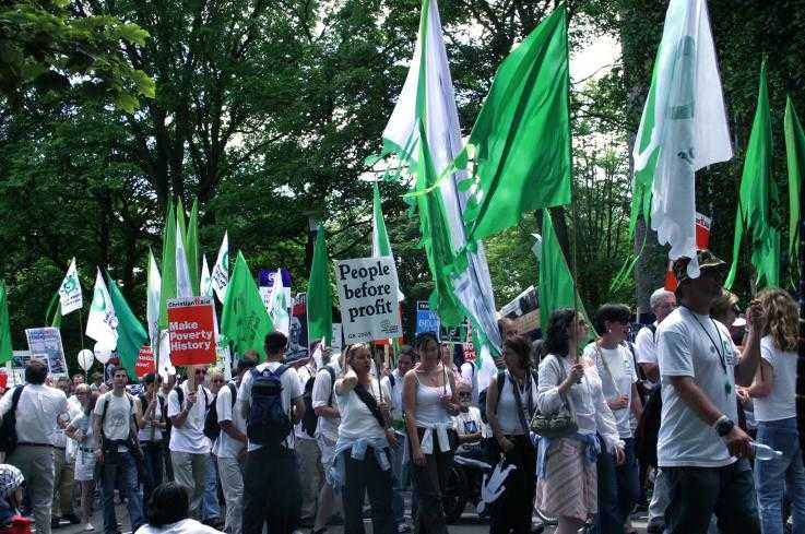 Activists marching with green and white flags, and placards