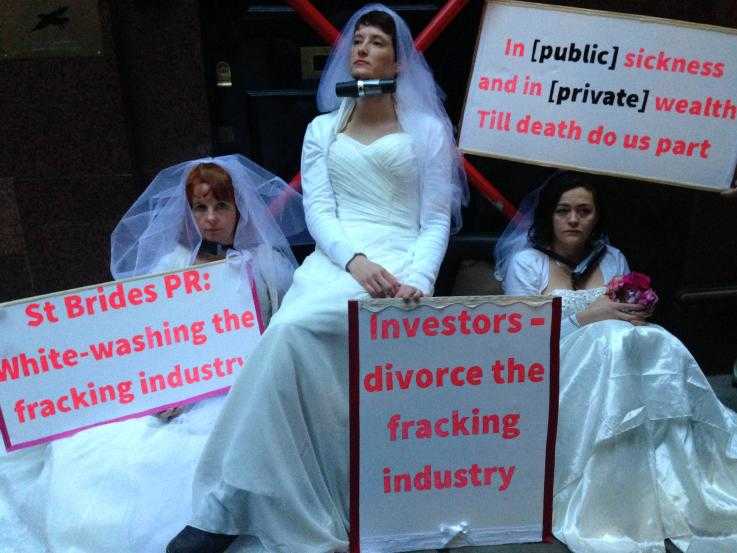 Three female protesters blockade the entrance of a PR company that supports the fracking industry