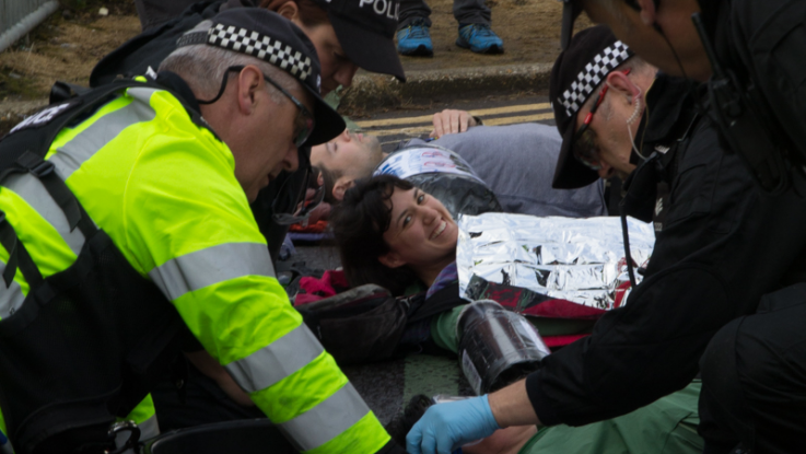 Police try to remove a protester from a lock-on blockade